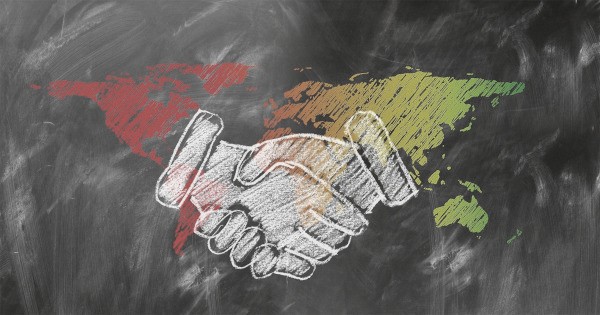 Chalk‑style handshake on a world map representing global cooperation and openness